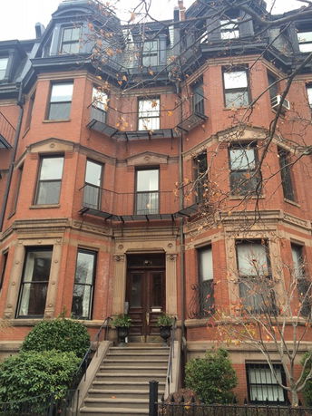 Front view of a multi-story brick building with balconies and bay windows.