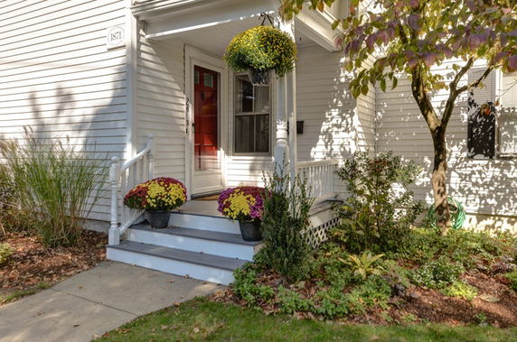 Front view of a house with a porch and red door.
