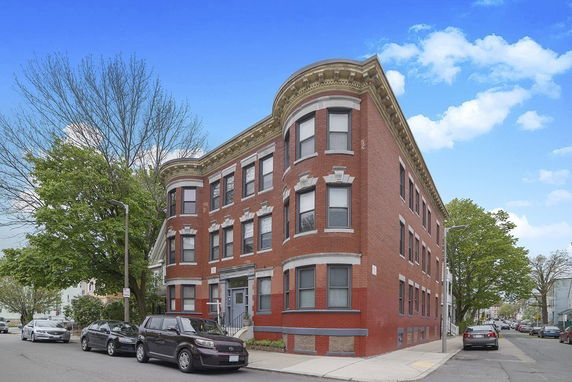Front view of a red brick three-story apartment building.