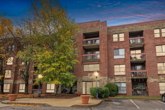 Front view of a multi-story brick apartment building with balconies.
