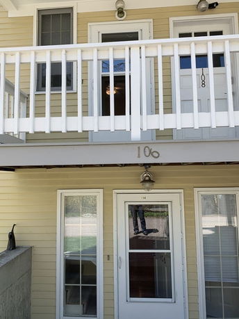 Front view of a multi-story building with doors marked 106 and 108, and a balcony railing.