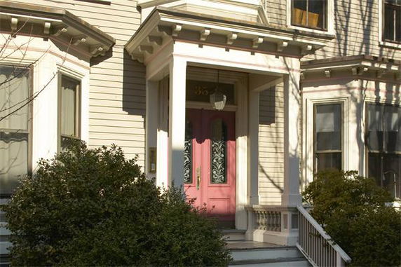 Front view of a house with a prominent pink door and decorative trim.