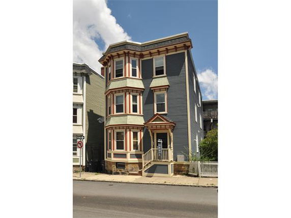 Front view of a three-story house with a decorative facade and bay windows.