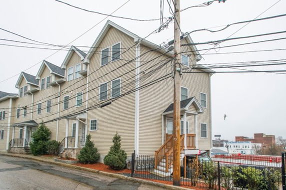Front view of a multi-story residential building with gabled roofs and multiple windows.