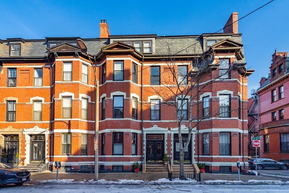 Front view of a multi-story brick townhouse with large windows and a central entrance.