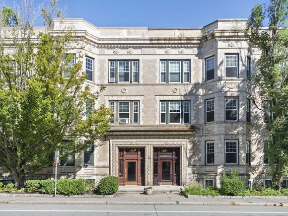 Front view of an ornate three-story building with large windows and a decorative entrance.
