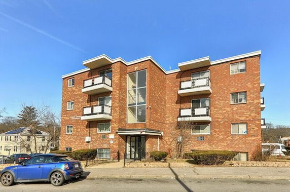 Front view of a multi-story brick apartment building with balconies.
