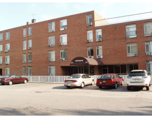 Front view of a multi-story brick building with parking area in front.