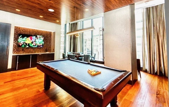 Room with a billiards table and a mounted television.