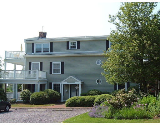 Front view of a three-story house with balconies and dark shutters.