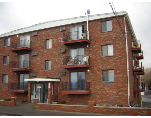 Front view of a multi-story brick apartment building with balconies.