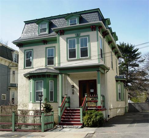 Front view of a multi-story house with decorative green accents and a steep roof.