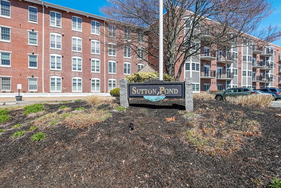 Front view of a multi-story brick building with a sign reading 'Sutton Pond'.