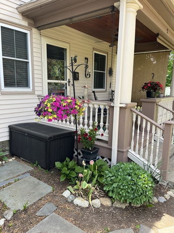 Front view of a house with a porch and hanging flower basket.
