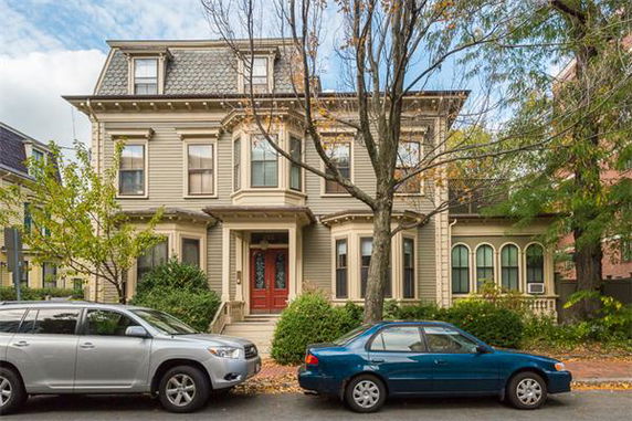 Front view of a multi-story house with a distinct architectural design and a red front door.