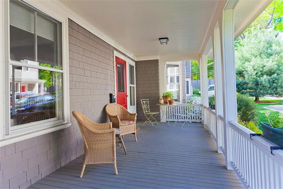 Porch view of a house with wicker chairs and railing, overlooking the neighborhood.