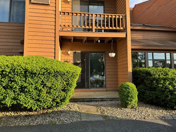 Front view of a house with wooden exterior and a small balcony above the entrance.