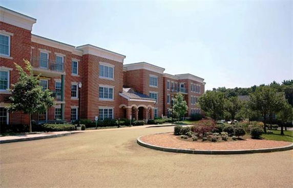 Front view of a three-story brick building with multiple windows and a circular driveway.