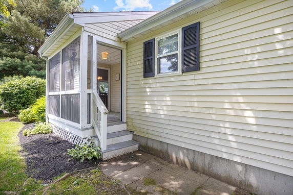 Side view of a house with a screened porch and yellow siding.
