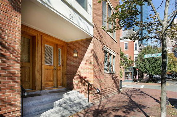 Front view of a brick building with wooden doors and stairs leading up.