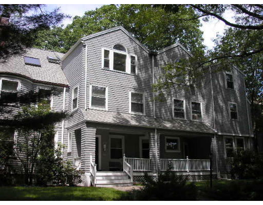 Front view of a multi-story residential building with grey siding and white trim.