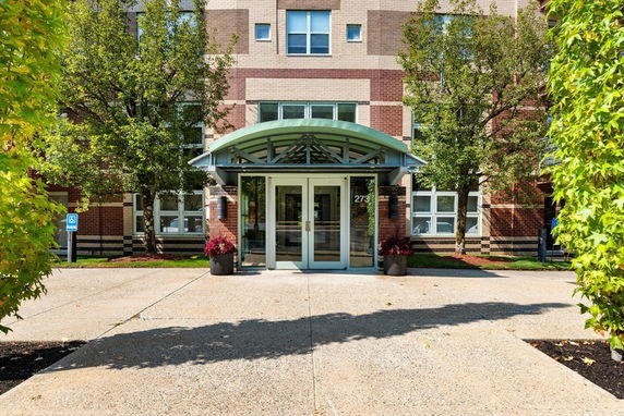 Front view of a brick building entrance with a glass door and canopy.