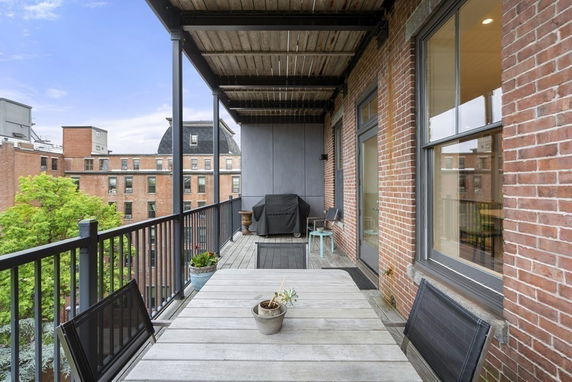 Outdoor patio view from a building with seating area and nearby buildings visible.