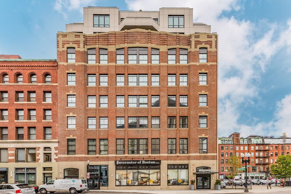 Front view of a multi-story brick building with large windows.