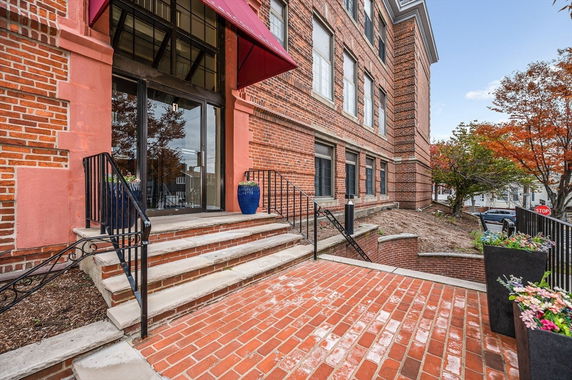 Front view of a brick building with a glass entrance and red canopy.