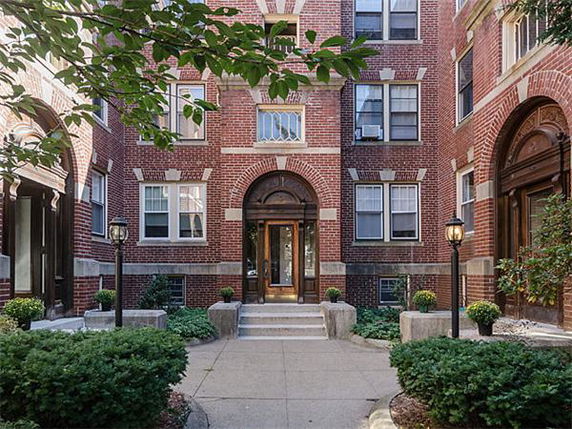 Front view of a brick apartment building with arched entrance.