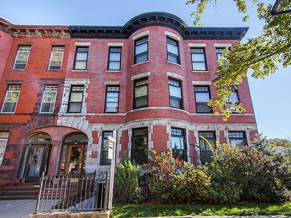 Front view of a multi-story brick building with large windows and an arched entrance.