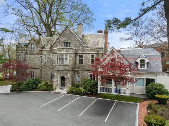 Front view of a large stone mansion with a complex roof design.