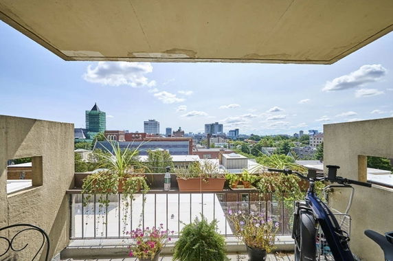 Balcony view overlooking a cityscape with various buildings on a clear day.