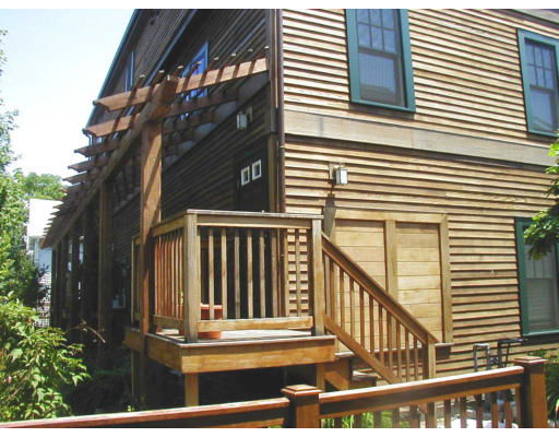 Side view of a two-story wooden house with a porch and railing.