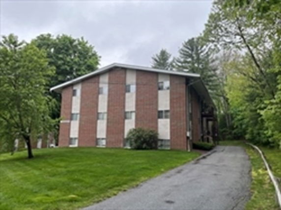 Front view of a multi-story brick building with a sloped roof.