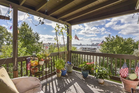 A covered outdoor balcony with potted plants and a view of the city skyline in the distance.