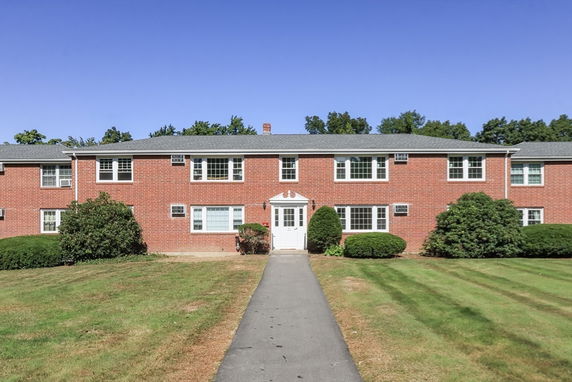Front view of a two-story brick apartment building with multiple windows and a central entrance.