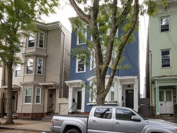 Front view of a three-story townhouse with distinct blue siding and white trim.