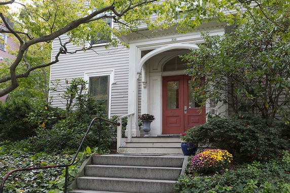 Front view of a house with a red door and a small staircase leading to the entrance.