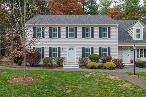 Front view of a two-story house with black shutters and a grey roof.