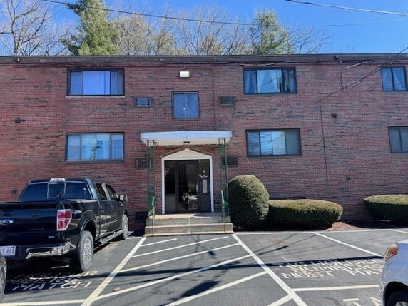 Front view of a two-story brick apartment building with multiple windows and a central entrance.