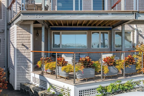Front view of a house with a balcony and railing, featuring decorative plants.