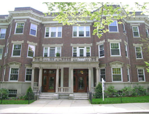 Front view of a multi-story brick building with multiple windows and decorative columns at the entrance.