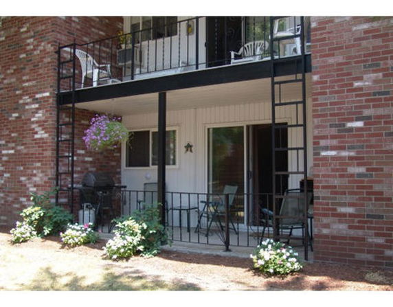 Front view of a two-story building with balconies and patio seating.