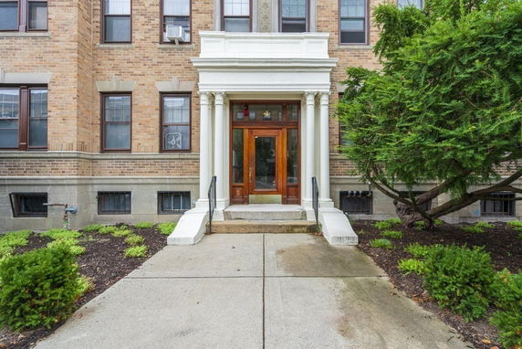 Front view of a multi-story brick building entrance with columns.