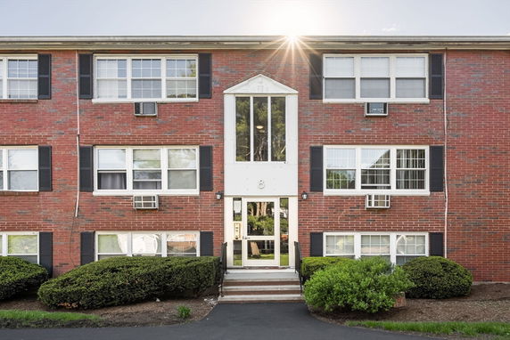 Front view of a three-story brick apartment building with multiple windows.