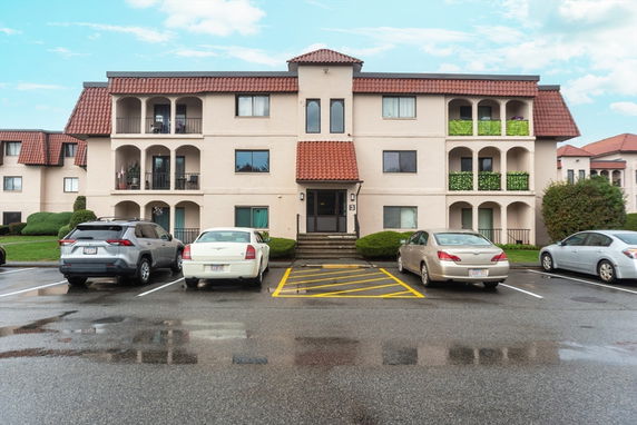 Front view of a three-story apartment building with balconies and terracotta roofs.
