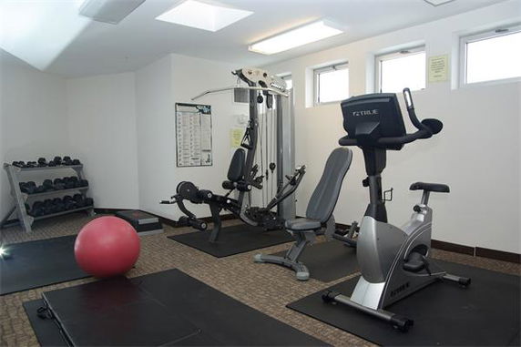 Room equipped with fitness equipment including a weight machine, exercise bike, and dumbbells.
