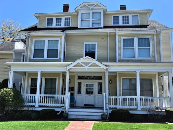 Front view of a multi-story house with a large porch and white trim.