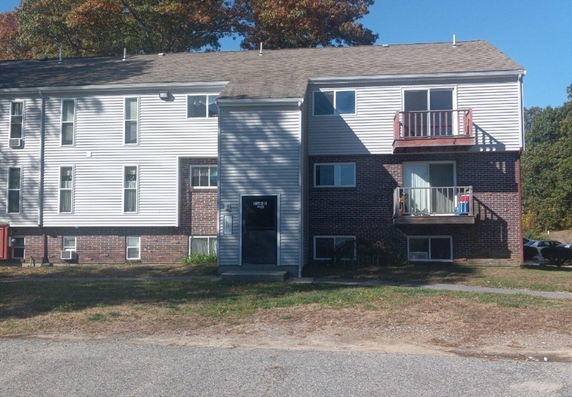 Front view of a multi-story residential building with balconies and a brick facade.